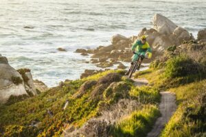 Mountain biker riding trail along scenic coastline at sunset