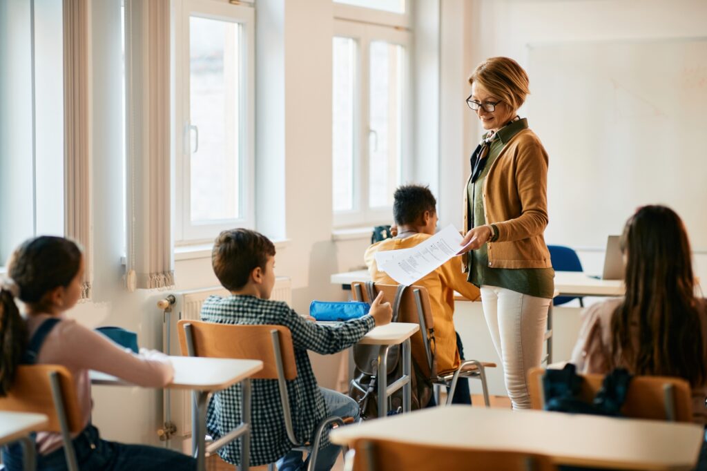 teacher giving a paper to her student during a class at primary school in Cyprus.