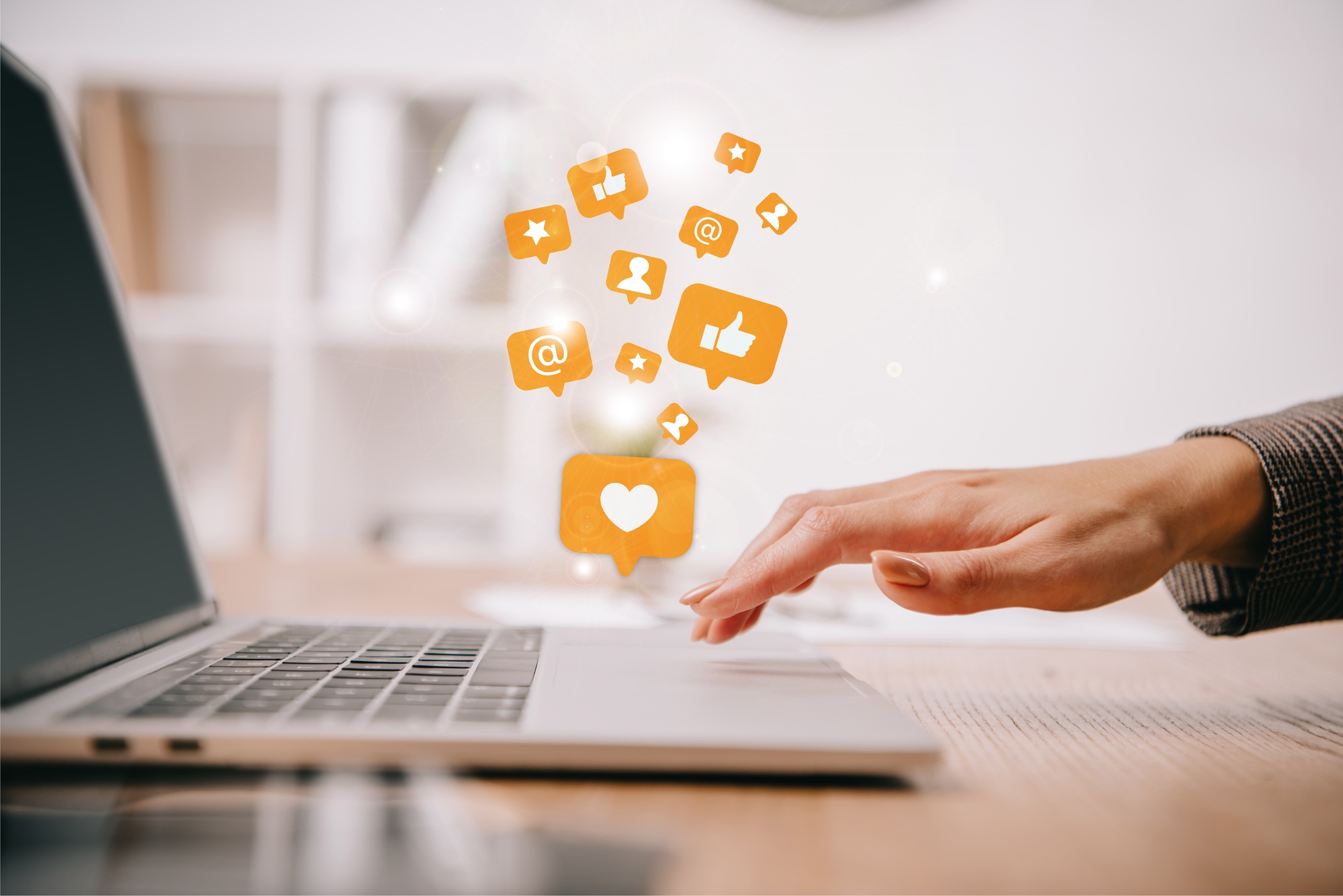 cropped view of businesswoman typing on laptop at workplace with multimedia icons