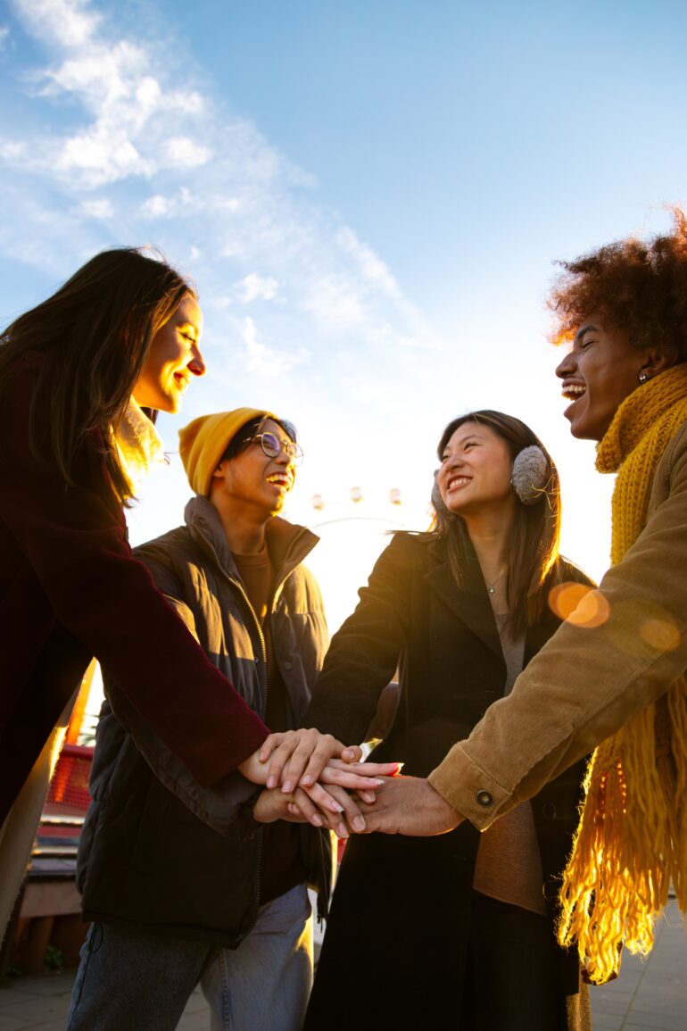 Multiracial friends stacking hands together in a circle as symbol of community, friendship. Vertical