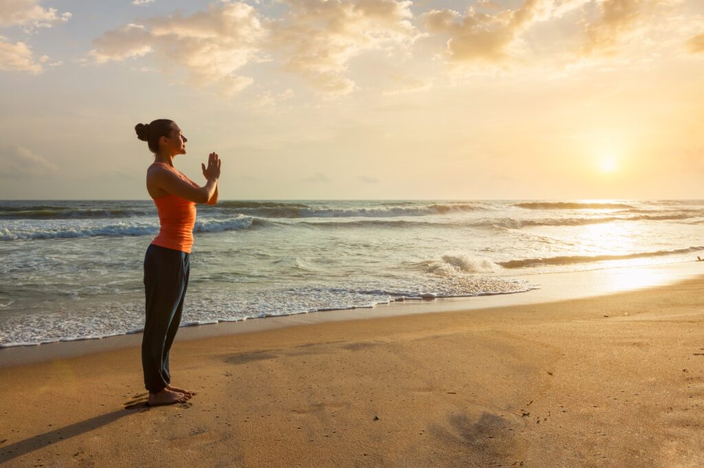 Woman practicing yoga on the beach in Cyprus, embracing wellbeing in Cyprus.